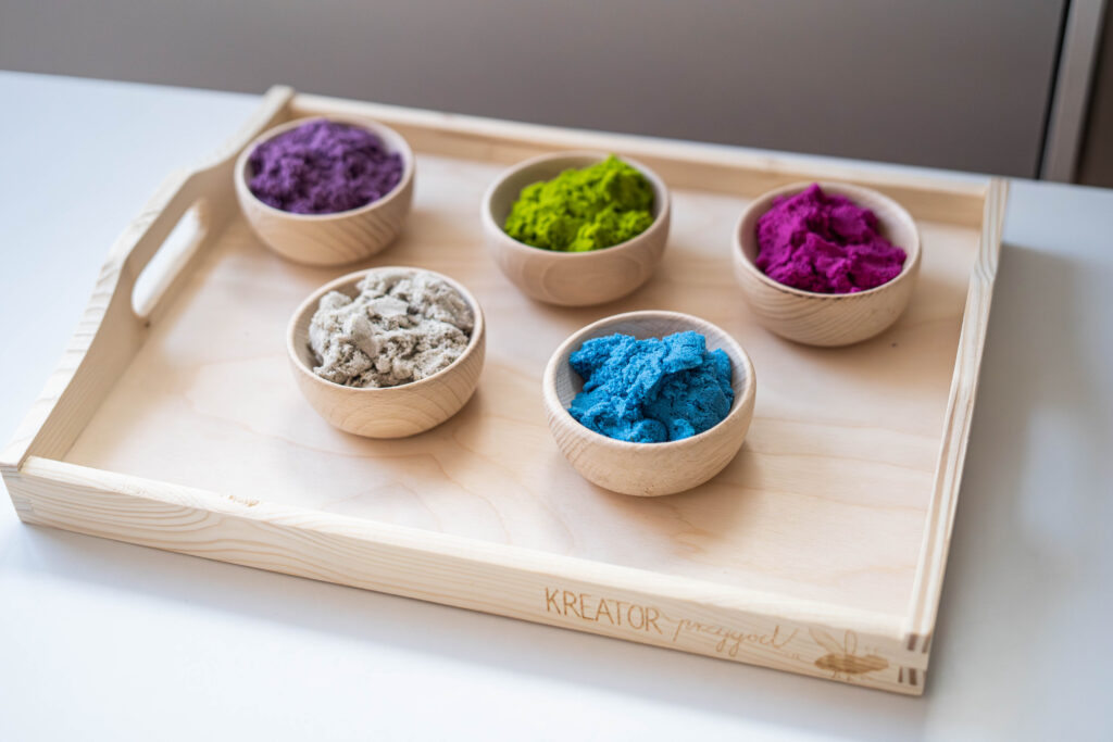 pięć kolorów piasku dynamicznego ułożone na drewnianej tacy